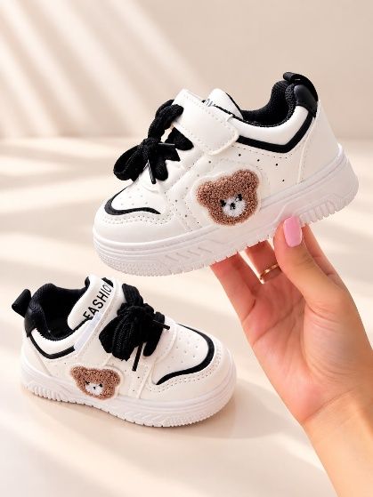 Tenis blancos con un osito bordado y cordón negro